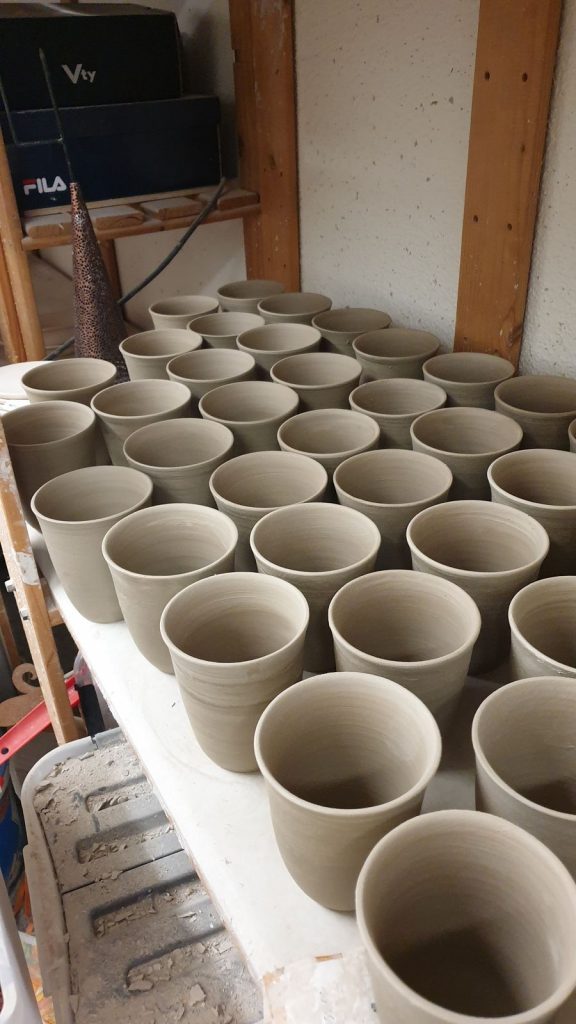 Kaffeebecher in der Keramikwerkstatt.
Auf der Töpferscheibe gedrehte Becher beim Trocknen.